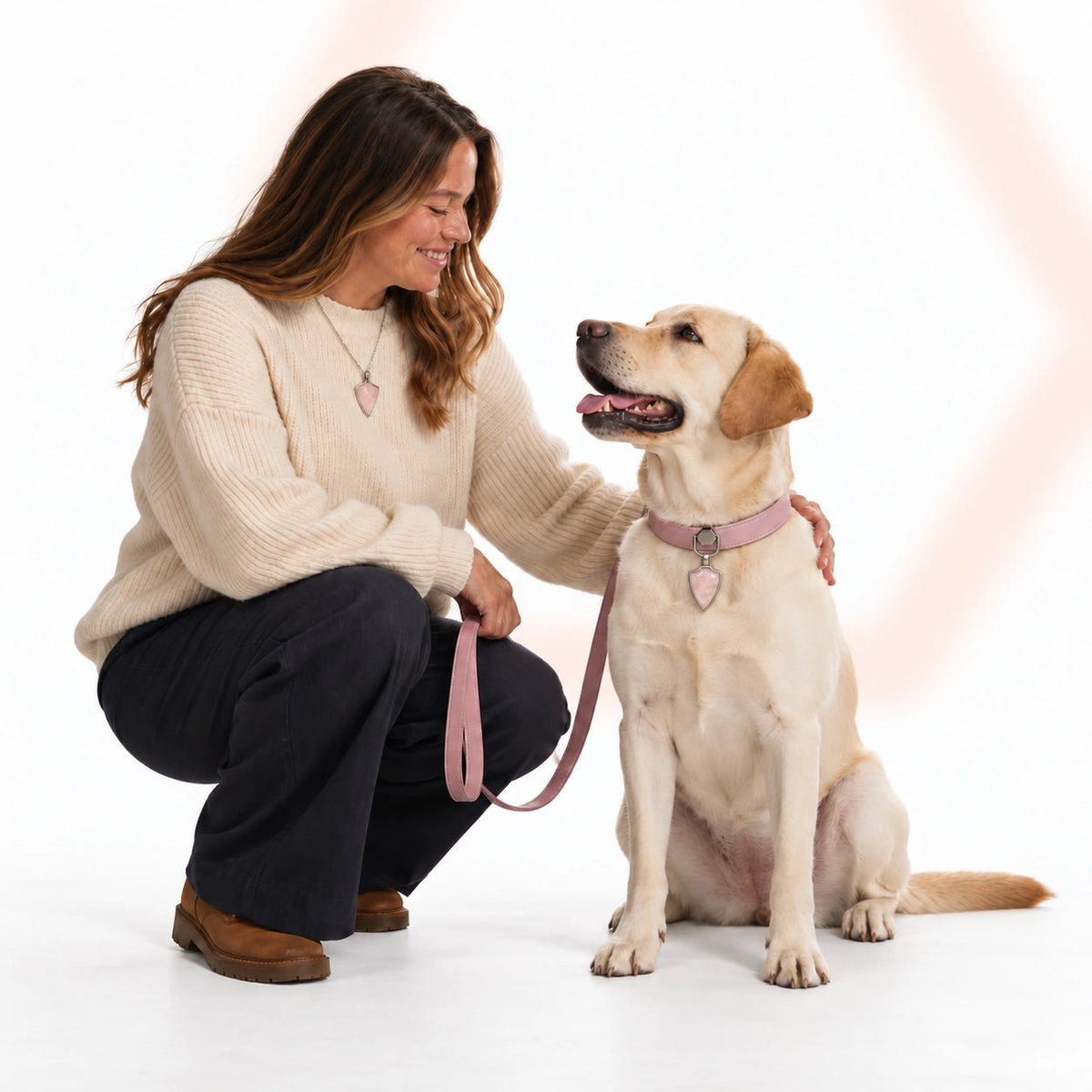 A woman and yellow Labrador wearing matching Rose Quartz accessories with a pink collar against a soft white backdrop.